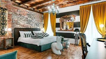 Une chambre avec un mur en briques, des poutres en bois au plafond, un lit avec des coussins à rayures, un miroir et des rideaux jaunes.