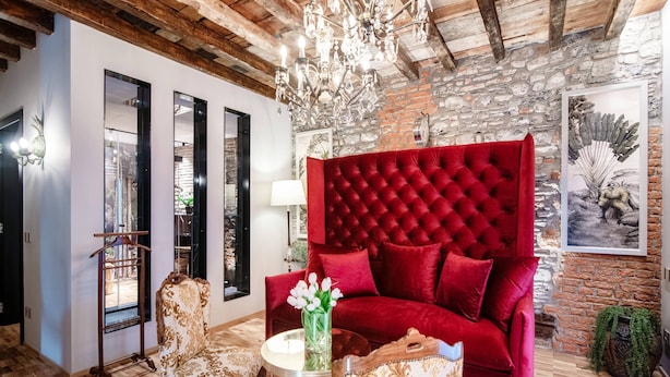 A room with a red velvet sofa, a chandelier, and a wooden ceiling. - Aurum - Como Luxury Suites (Como)