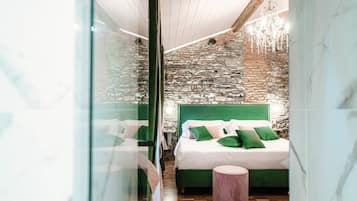 Una camera da letto moderna con una parete in pietra, una testiera imbottita verde e un pavimento in legno.