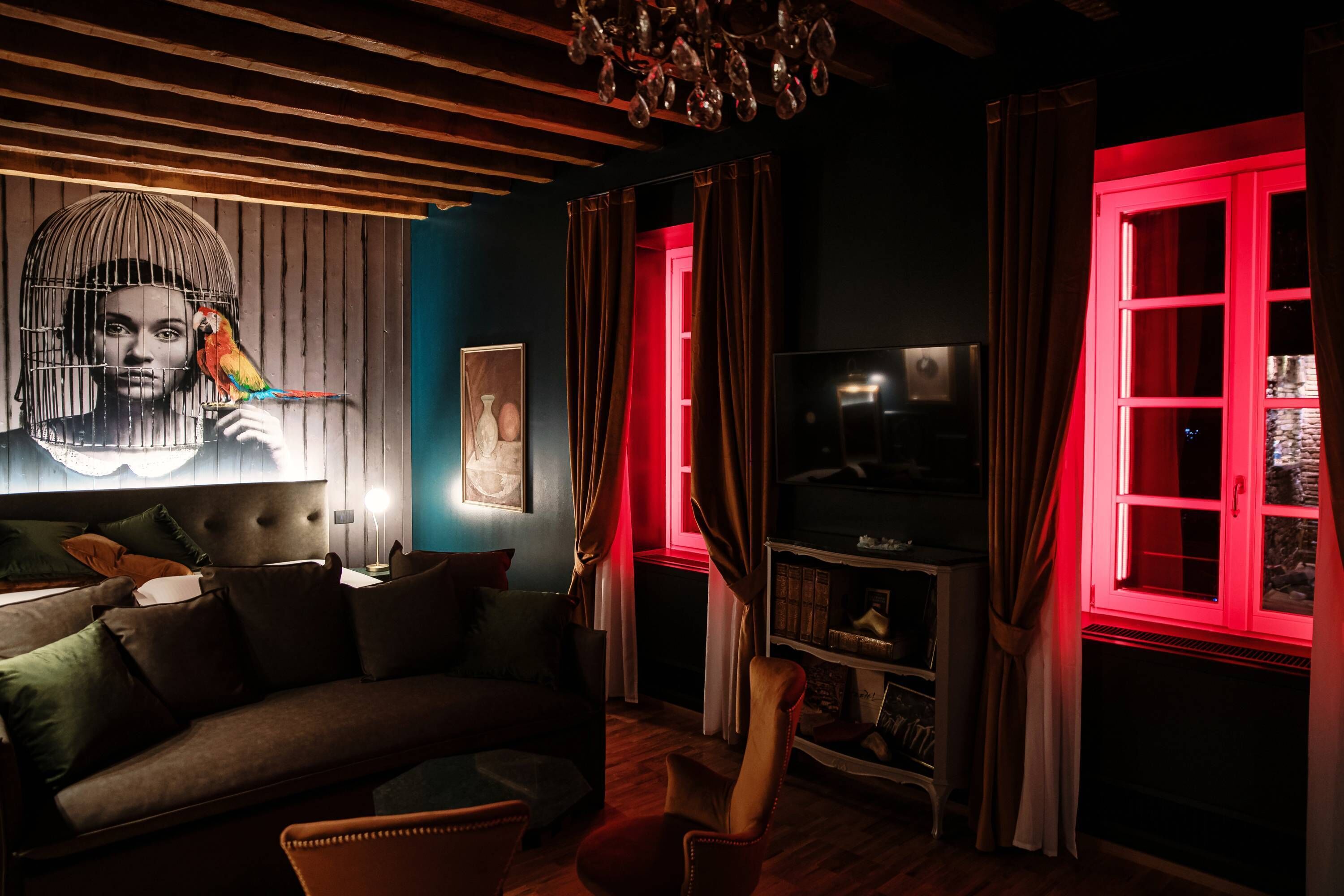 A cozy living room with a sofa, a television, and a red-lit window.