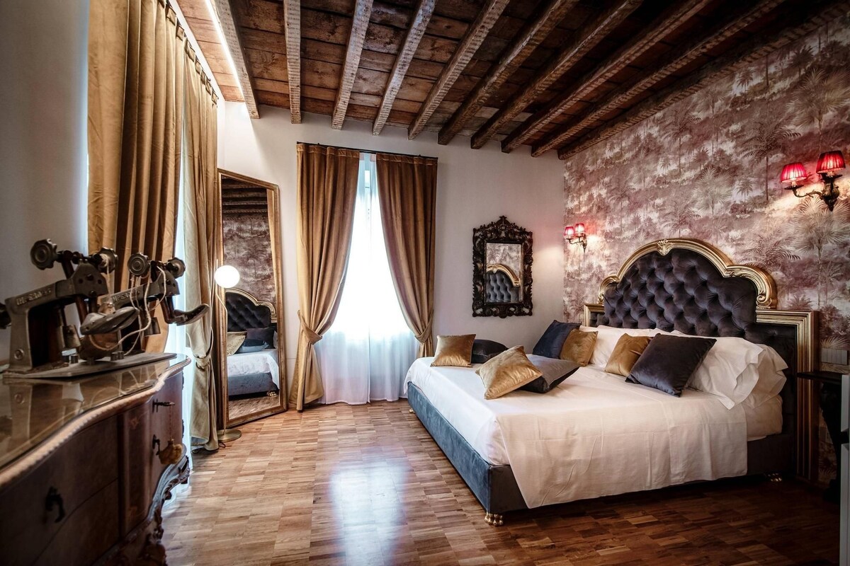 A bedroom with a large bed, wooden floor, and a decorative mirror on the wall.