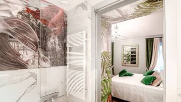 Un dormitorio con cama, almohadas verdes, un radiador blanco y una pared con diseño de hojas.