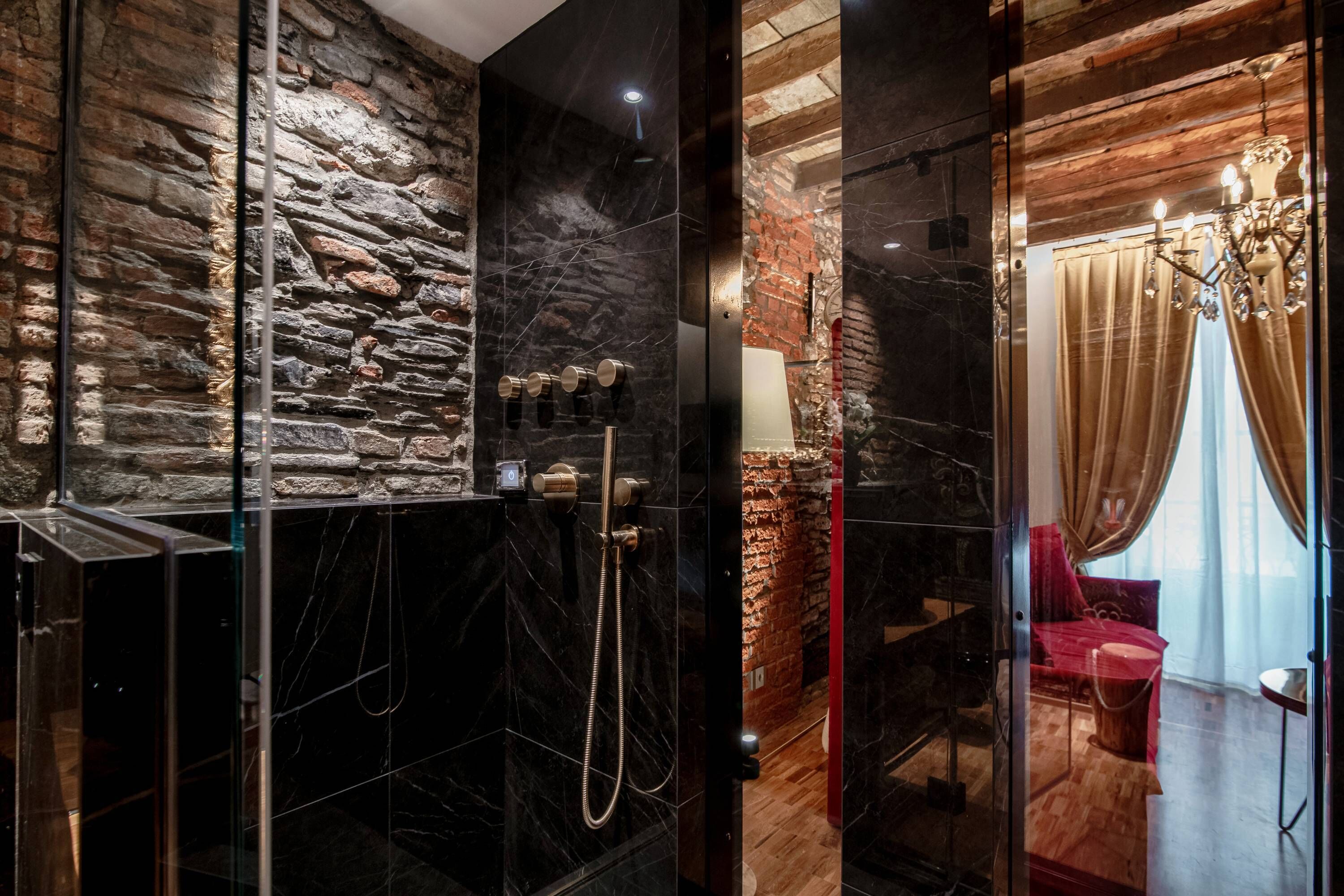 Ein modernes Badezimmer mit Steinwand, einer gläsernen Duschkabine und Holzboden.