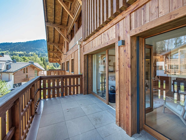 A wooden balcony with a view of a mountainous landscape.