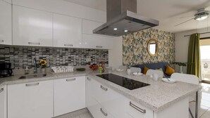 Een moderne keuken met witte kastjes, een granieten aanrechtblad en een spatwand met een geometrisch patroon.
