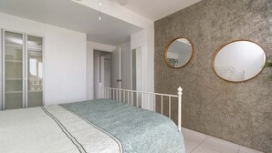Een slaapkamer met een bed, een kledingkast en een spiegel aan de muur.