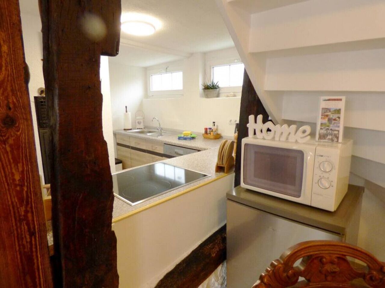Una cocina compacta con microondas, lavamanos y una pequeña encimera.