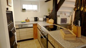 Una cocina con isla central, horno empotrado, microondas y un armario de madera.
