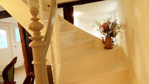 Una escalera con balaustres blancos y un florero con flores en la plataforma.