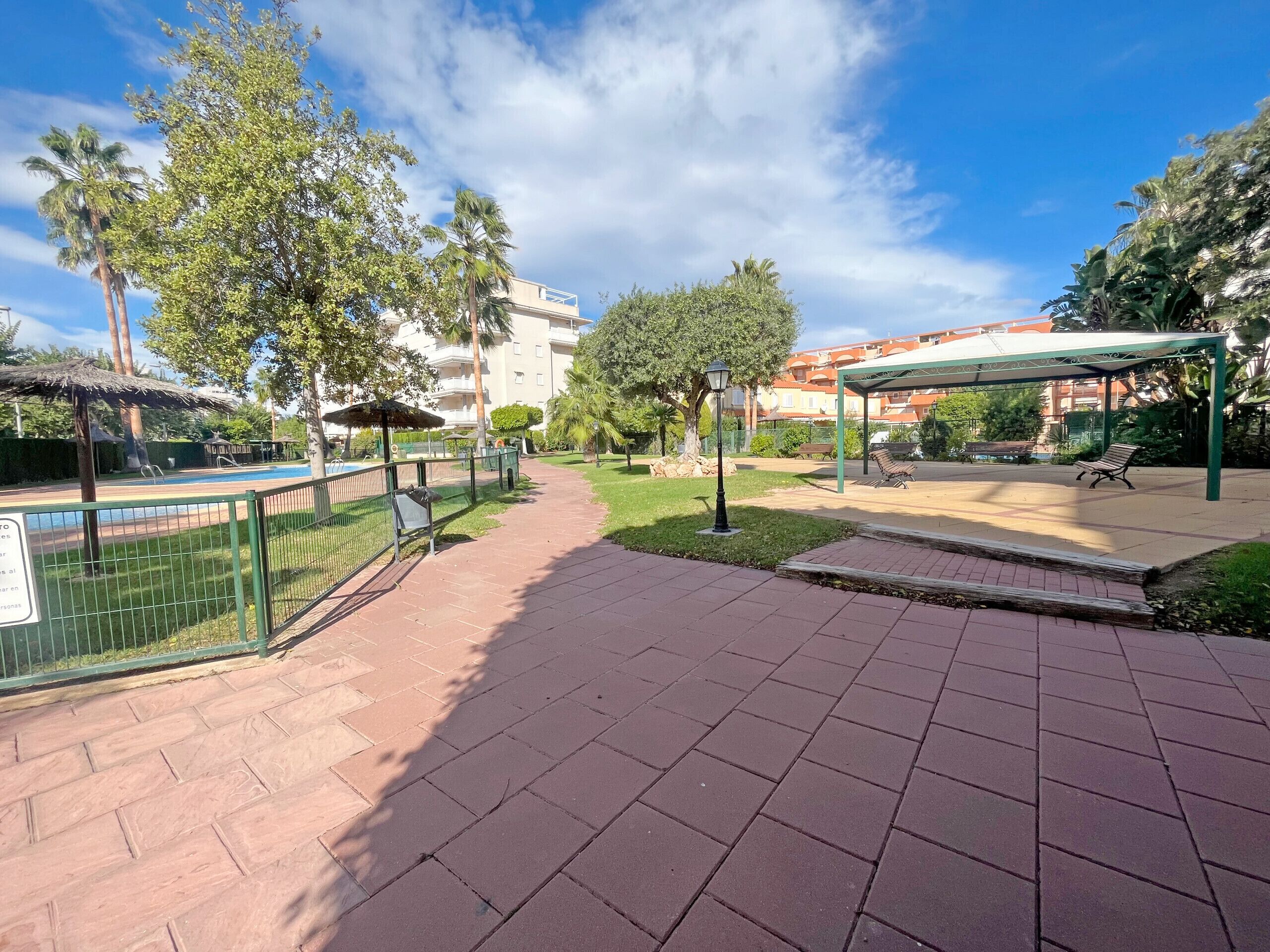 Un parc doté d’une allée pavée, de bancs, d’un espace de repos couvert et d’une piscine.