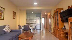 Una sala de estar con un sofá, una mesa de centro de madera y un mueble para televisión.