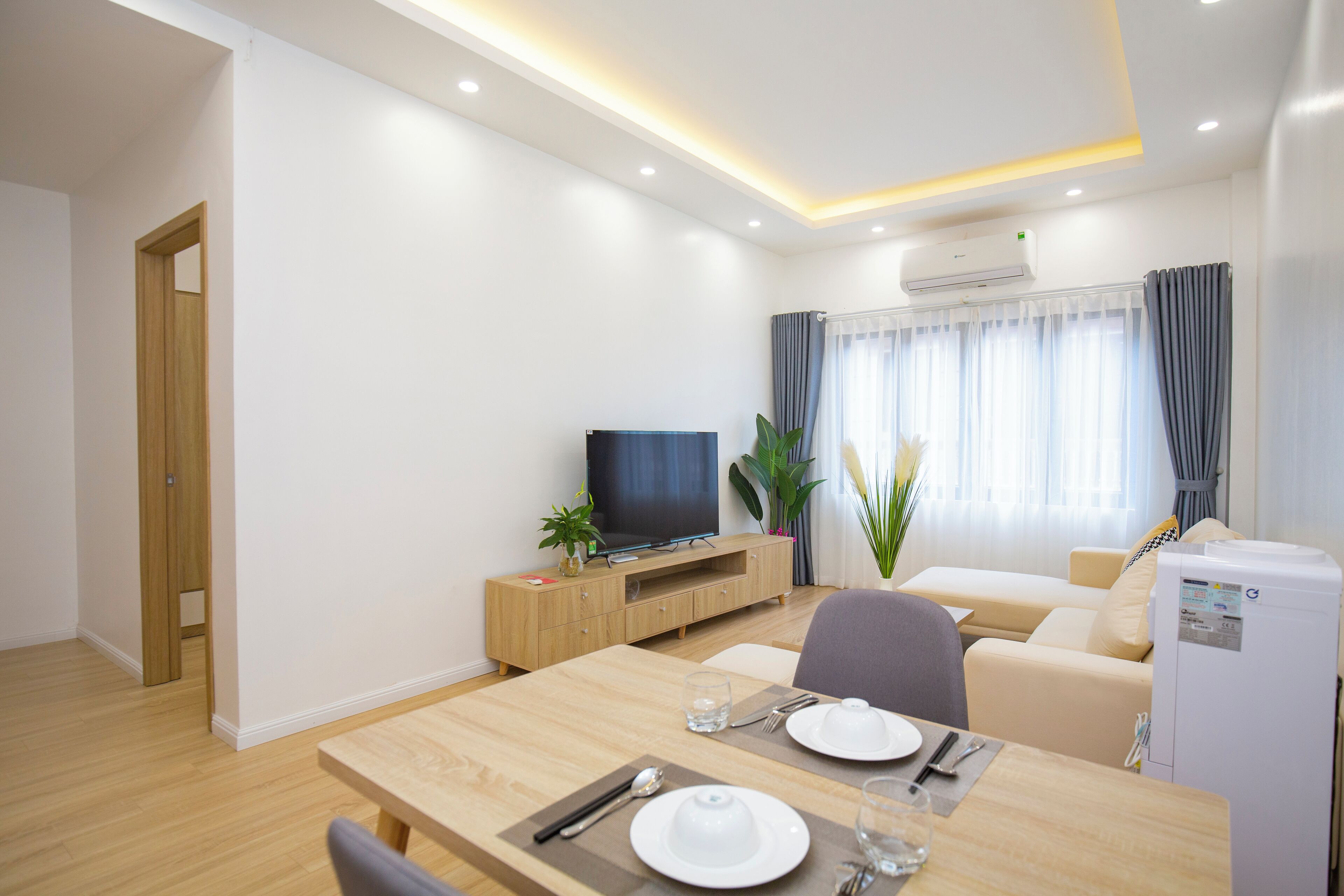 A modern living room with a dining area, a television, and a refrigerator.