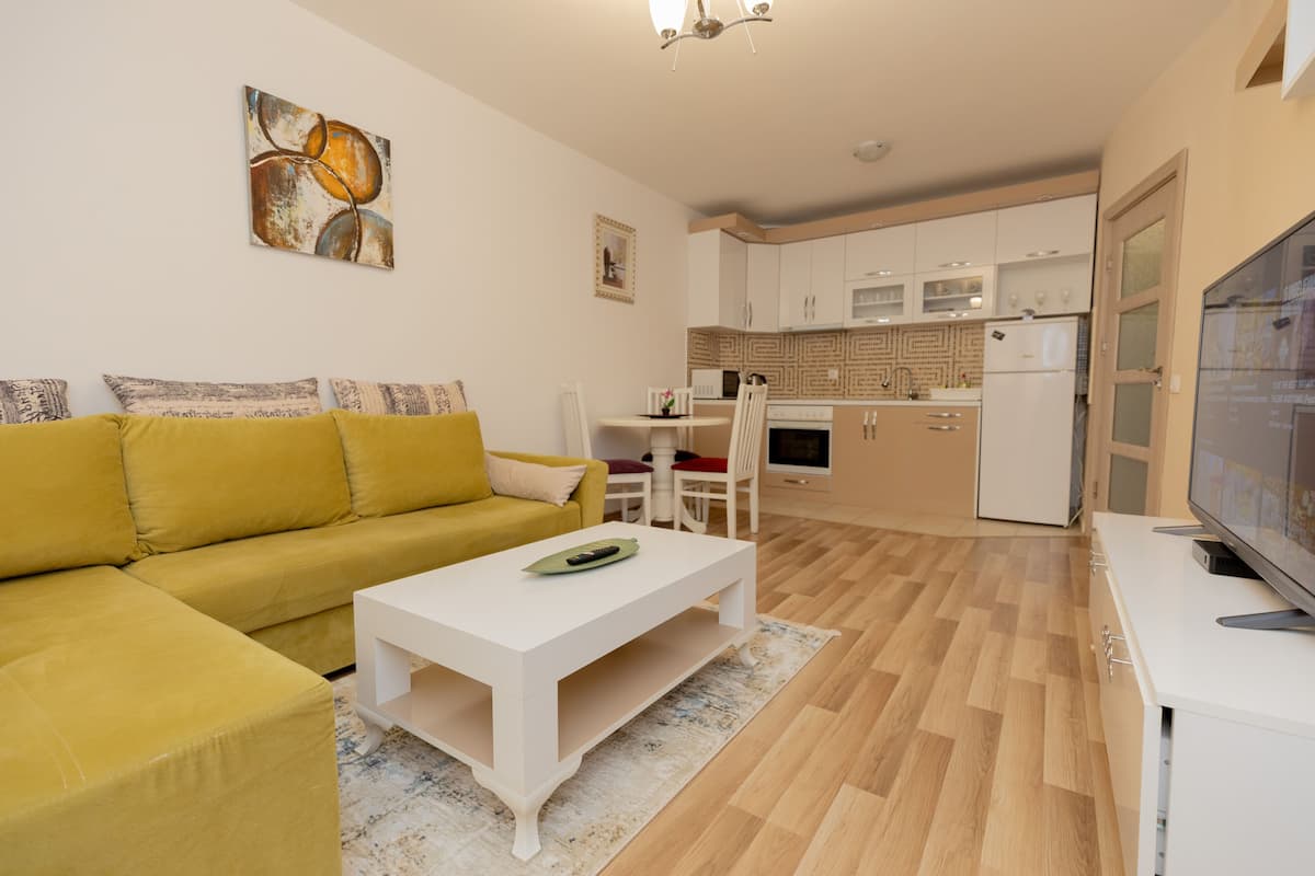 Ein modernes Wohnzimmer mit einem gelben Sofa, einem weißen Couchtisch und einem Fernseher auf einem Lowboard.