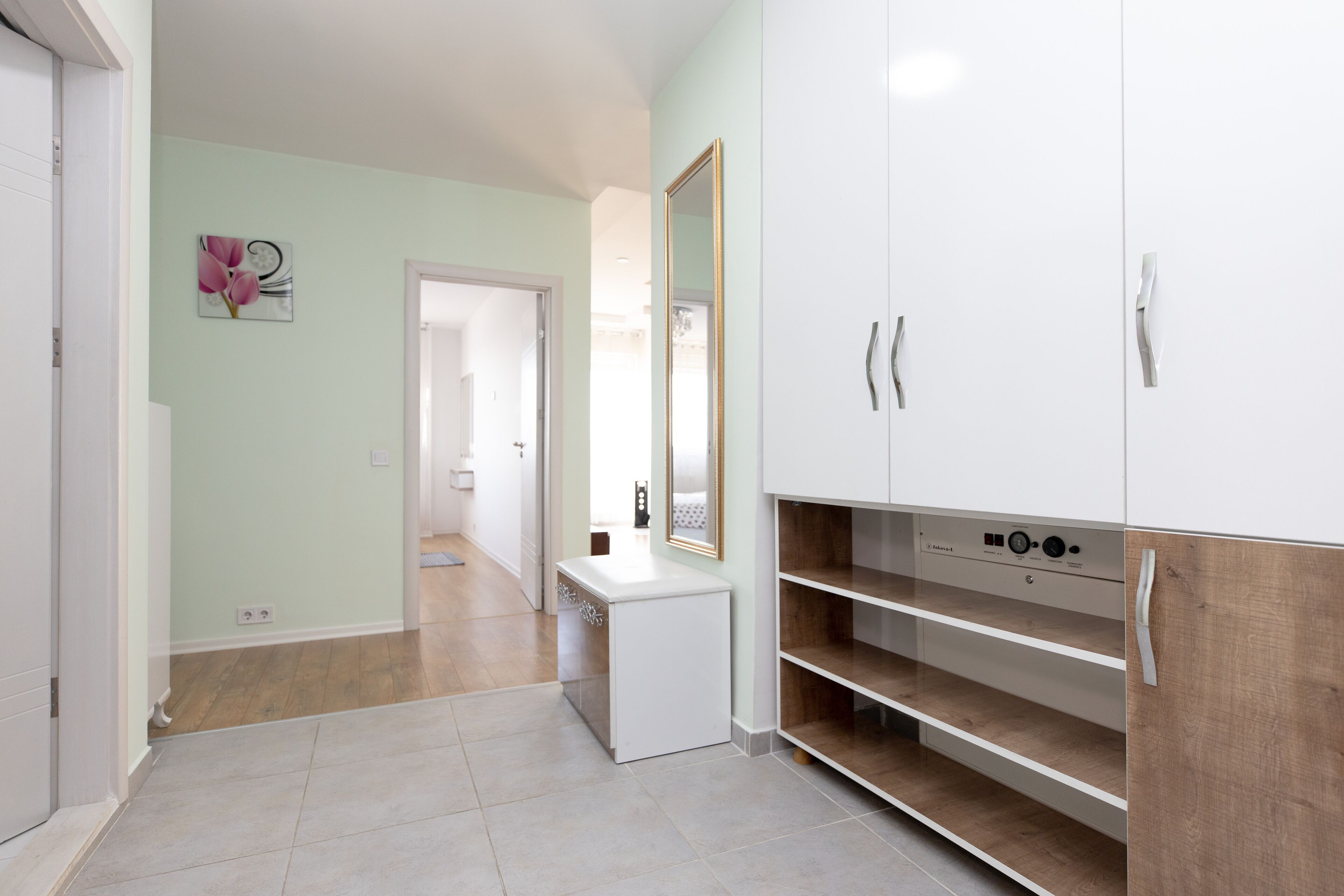 Un pasillo moderno y bien iluminado con una consola blanca, un espejo grande y estanterías empotradas de madera.