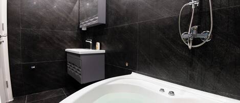 Un baño moderno con una bañera independiente, un tocador con espejo y un cabezal de ducha.