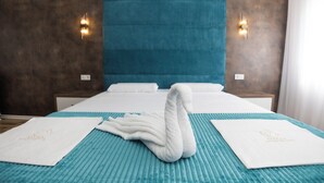 Habitación de hotel con una cama grande, ropa de cama color turquesa y dos lámparas de pared.