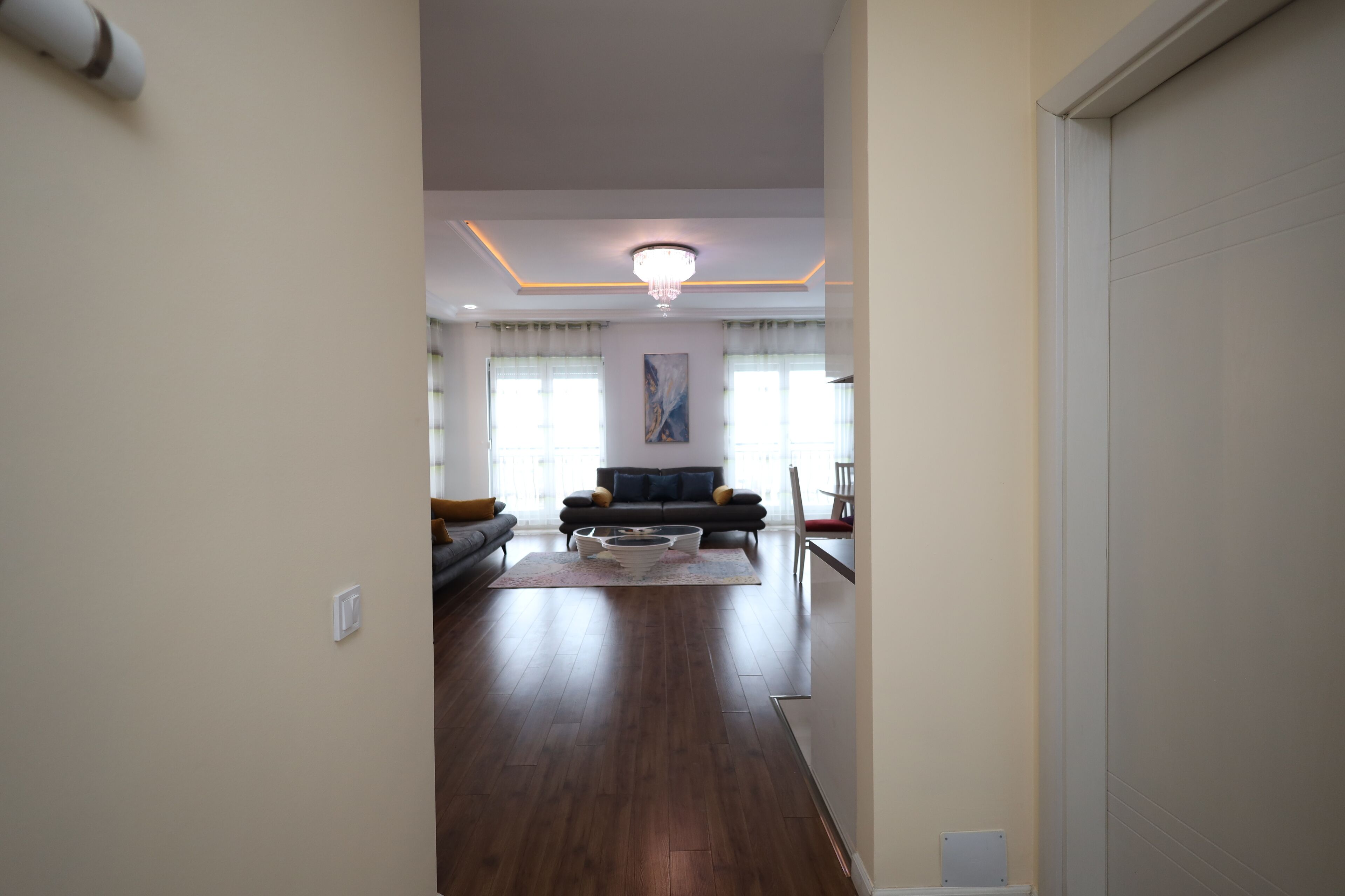 A spacious living room with a dark wooden floor, a sofa set, and a coffee table.