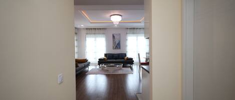 A spacious living room with a dark wooden floor, a sofa set, and a coffee table.