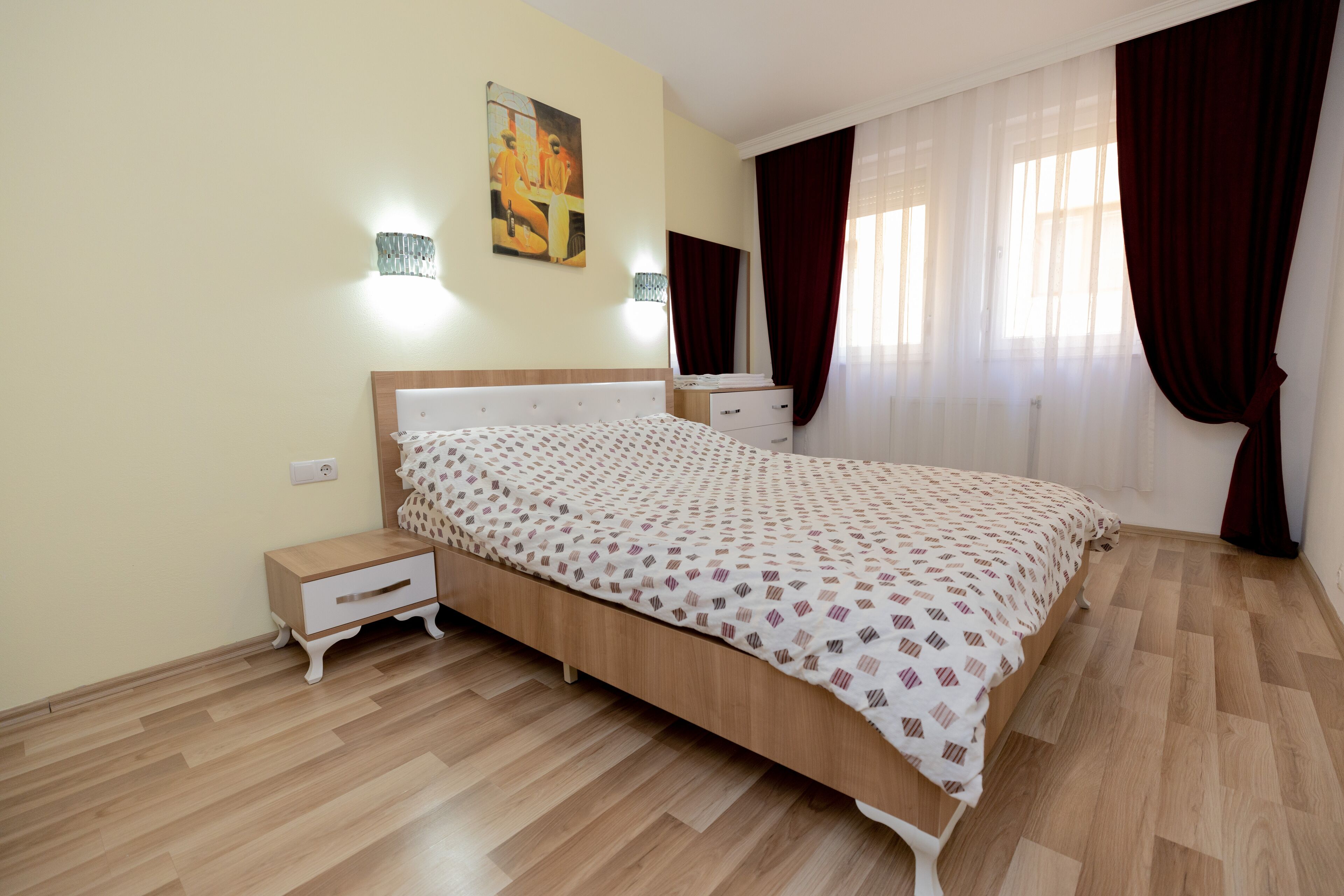 Un dormitorio con cama de madera, mesitas de noche y un buró.