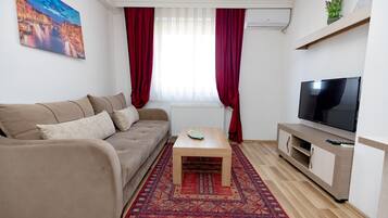 A living room with a sofa, coffee table, TV, and a patterned rug.