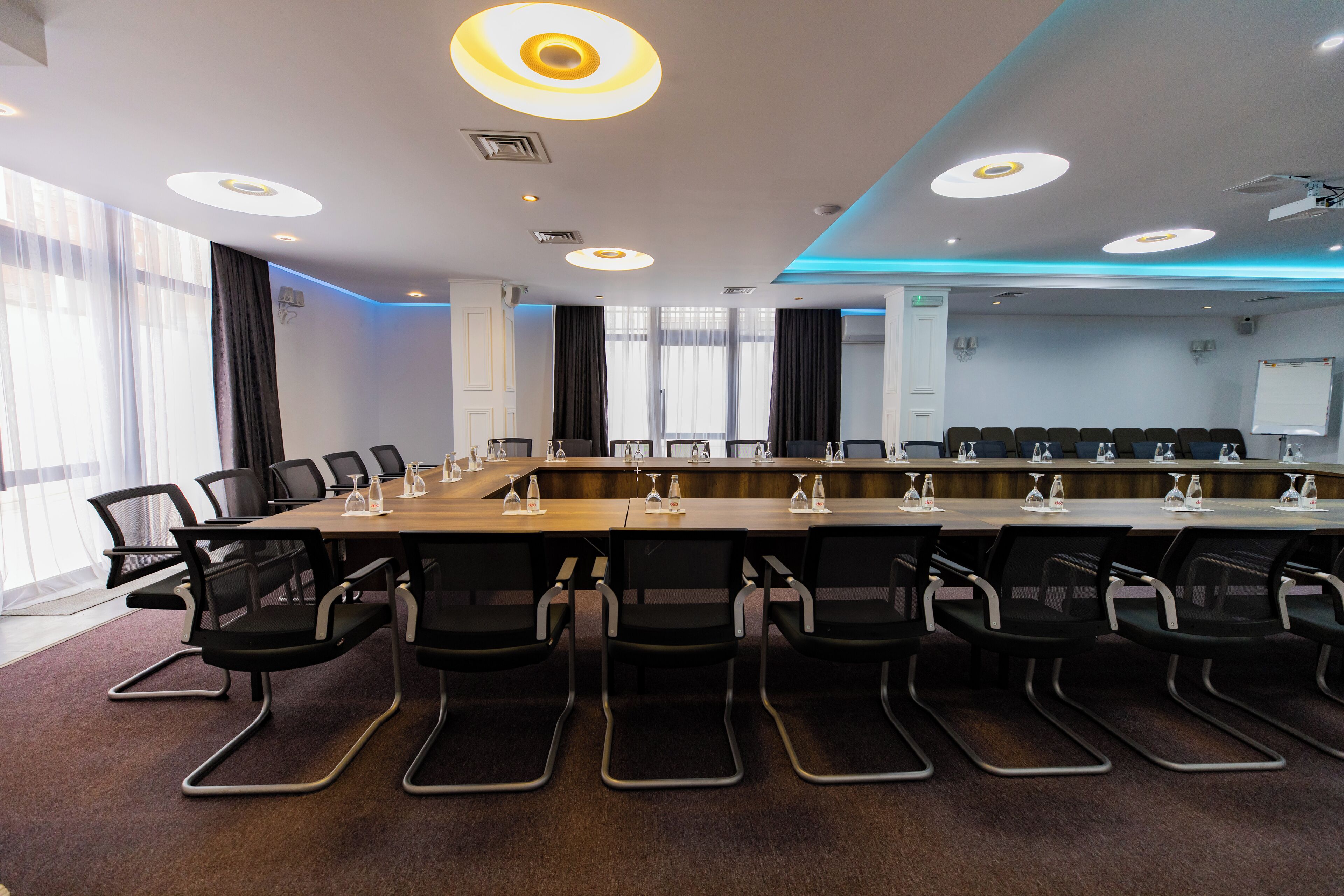 A conference room with a long table, black chairs, and a whiteboard.