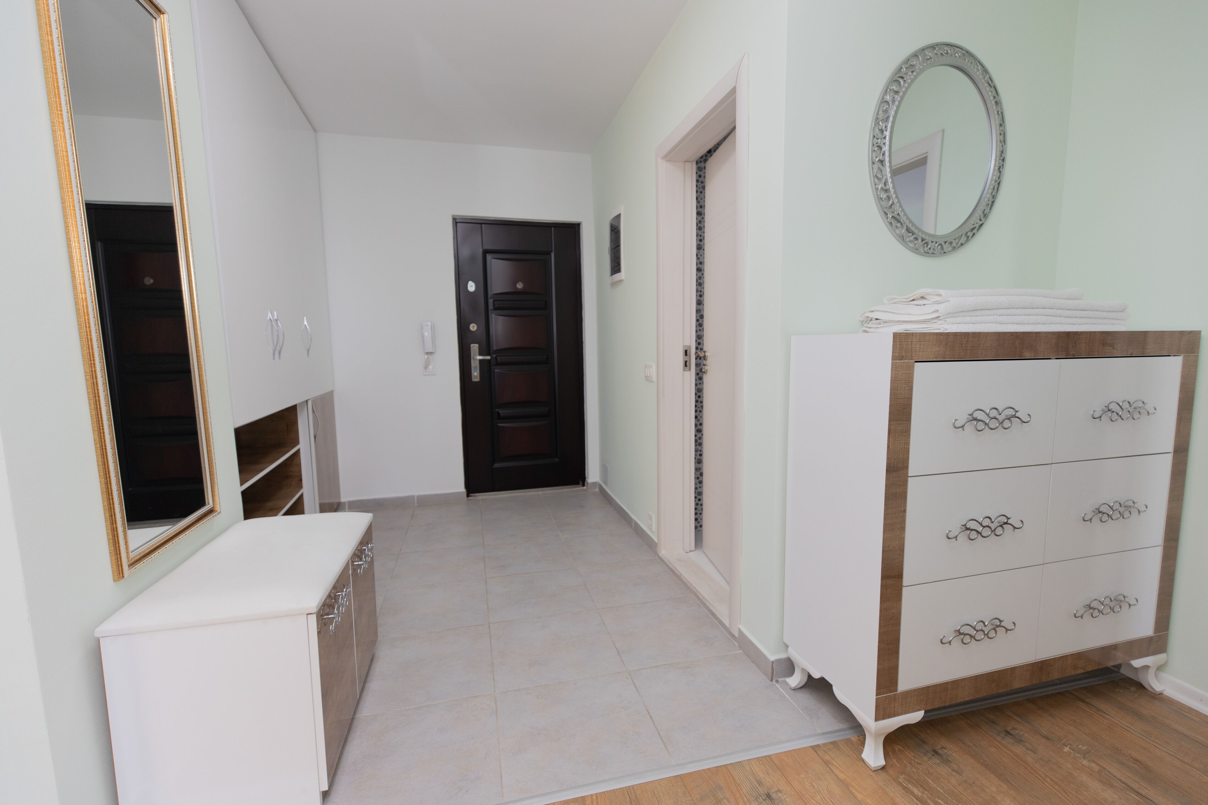 A hallway with a white console table, a wooden cabinet, and a dresser with drawers.