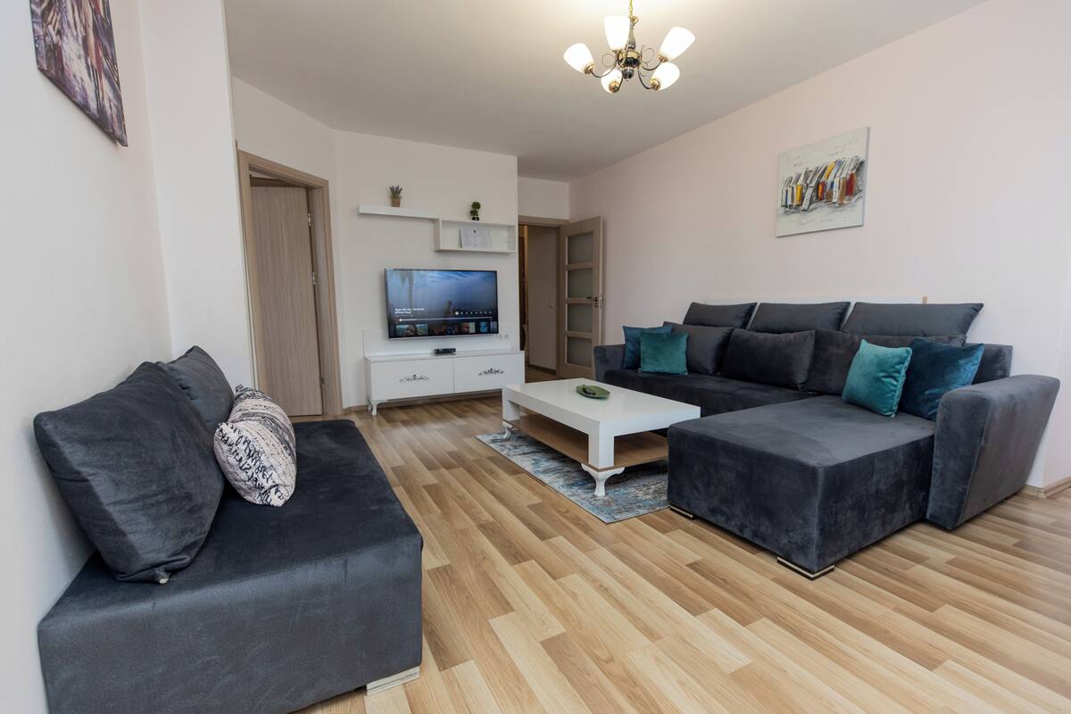 Ein modernes Wohnzimmer mit einem grauen Sofa, einem weißen Couchtisch und einem Fernseher auf einem Lowboard.