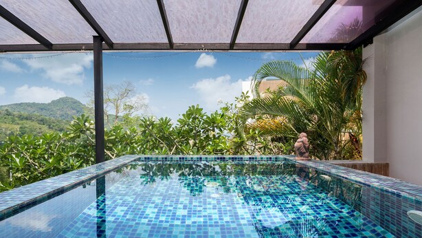 A clear blue pool with a tiled edge, surrounded by lush greenery and a view of distant hills. - Designer Sea View Villa Natural Touch A1 (Kamala)