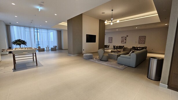 A spacious living area with a foosball table, comfortable seating, a dining area, and a large window with curtains.