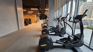 Et fitnessrum med løbebånd, crosstrainere og håndvægte.