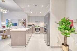 A modern kitchen with a central island, stainless steel appliances, and a dining area with a table and chairs.