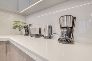 Eine Küche mit Kaffeemaschine, Toaster und einer Pflanze auf der Arbeitsfläche.
