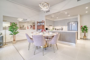 A modern kitchen with a central island, grey cabinets, and stainless steel appliances.