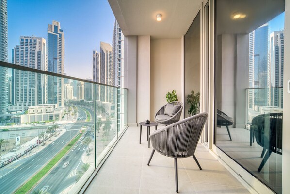 A balcony with a view of a cityscape, including tall buildings and a road.