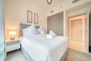 A hotel room with a bed, a nightstand, a lamp, a wardrobe, and a door.