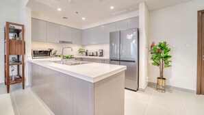A modern kitchen with a central island, stainless steel appliances, and light-colored cabinetry.