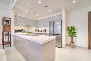 A modern kitchen with a central island, stainless steel appliances, and light-colored cabinetry.