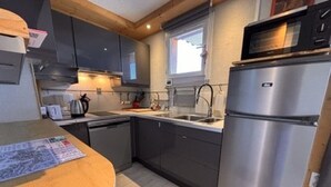 Een moderne keuken met donkere kastjes, een roestvrijstalen koelkast en een magnetron.