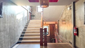Un escalier avec des marches en bois et un luminaire tressé suspendu au-dessus.