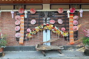 Une entrée d’immeuble de style traditionnel, avec une façade en briques, des parapluies décoratifs et une grande bûche en bois.