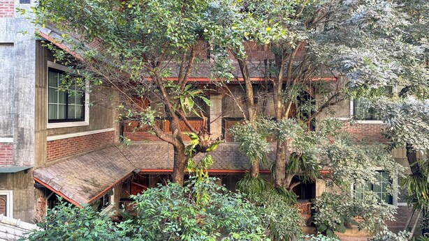 Un bâtiment traditionnel doté de nombreux balcons, avec un arbre en premier plan.