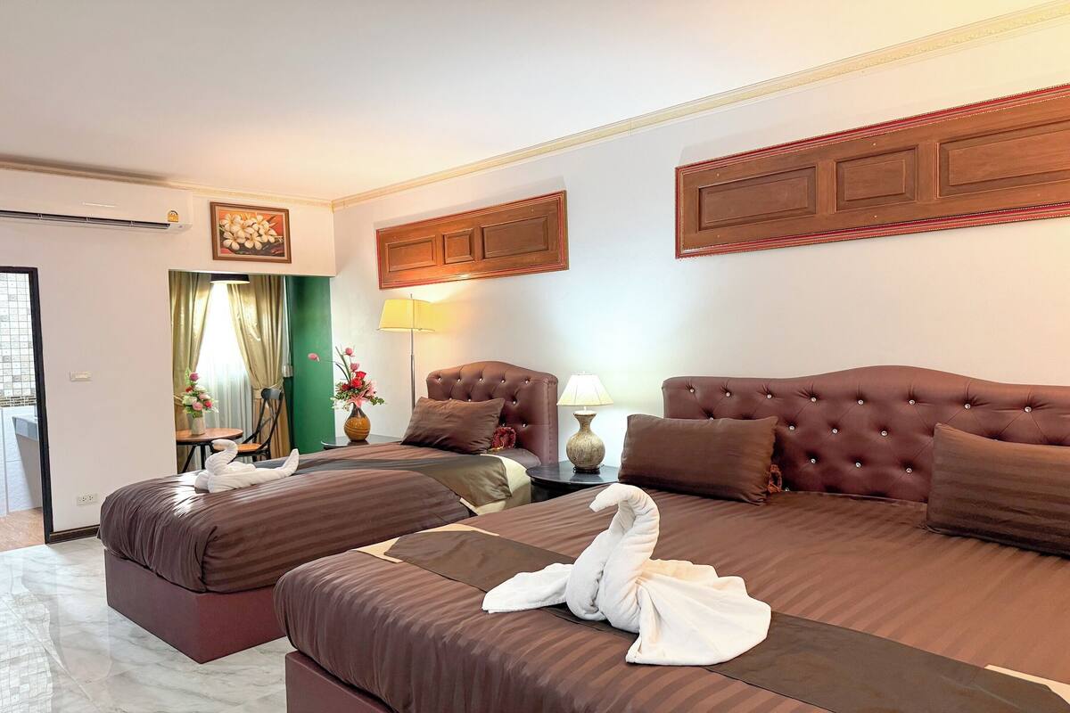 Ein Hotelzimmer mit zwei Betten, einer Sitzecke, einer Lampe und einer dekorativen Wandverkleidung.
