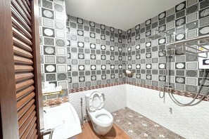 Une salle de bain avec un mur carrelé, des toilettes, un lavabo et un espace douche.