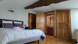 A bedroom with a bed, nightstand, and wooden doors leading to other rooms.