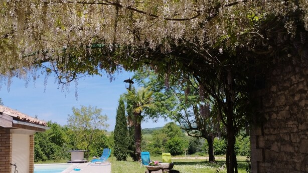 A patio area with a table and chairs, a pool, and a stone building.