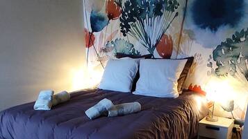 A bedroom with a bed, wooden flooring, and a wall mural.