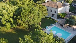 A large house with a swimming pool and lush greenery.