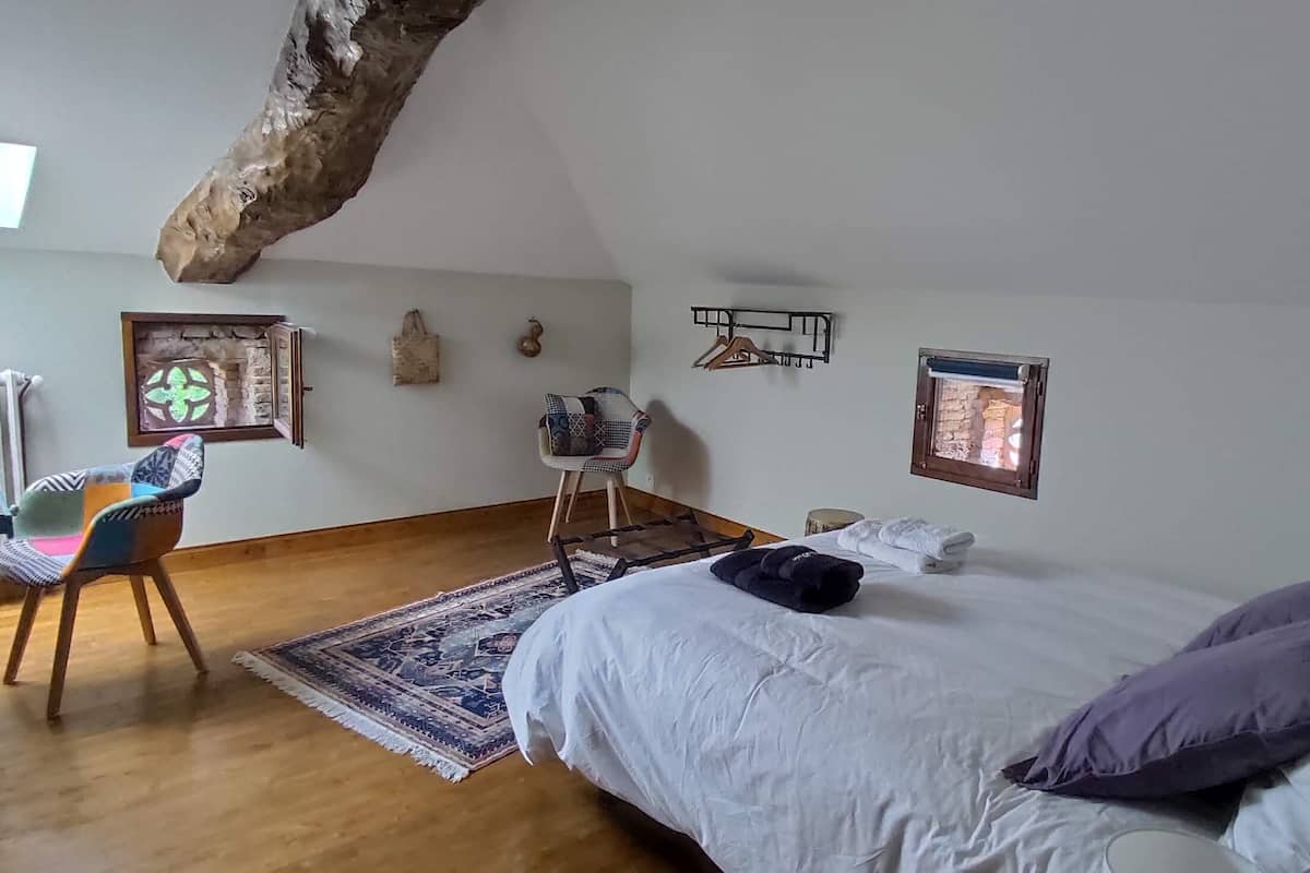 Ein Schlafzimmer mit einem Bett, einem Sessel, einem Tisch und einer Heizung.