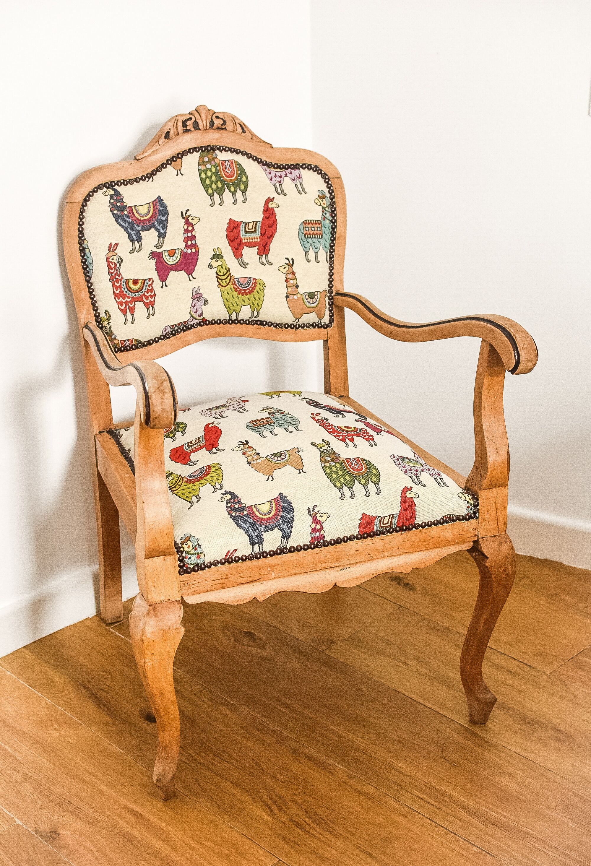 A wooden chair with a patterned cushion featuring colorful animal designs.