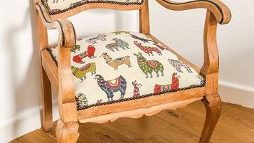 A wooden chair with a patterned cushion featuring colorful animal designs.